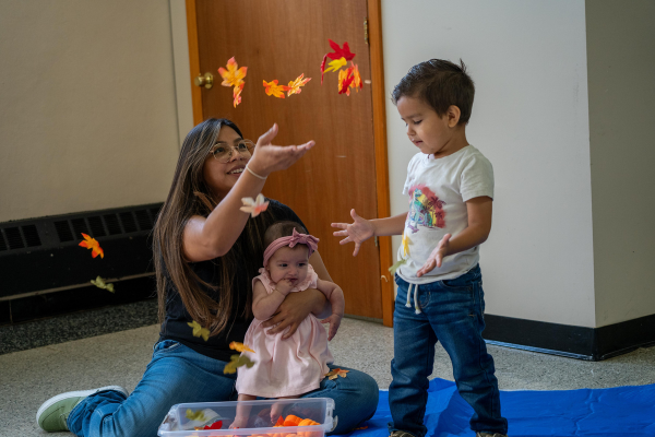  A mom throws leaves up for her young son to play